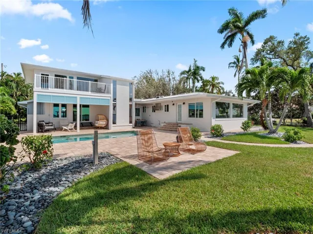 Back of property featuring a balcony, outdoor lounge area, a yard, a patio area, and an outdoor pool