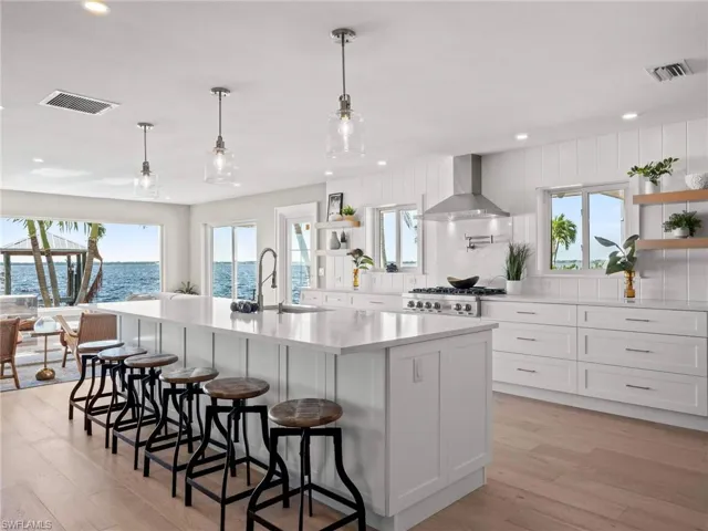 Kitchen with open shelves, a water view, light countertops, wall chimney exhaust hood, and white cabinets