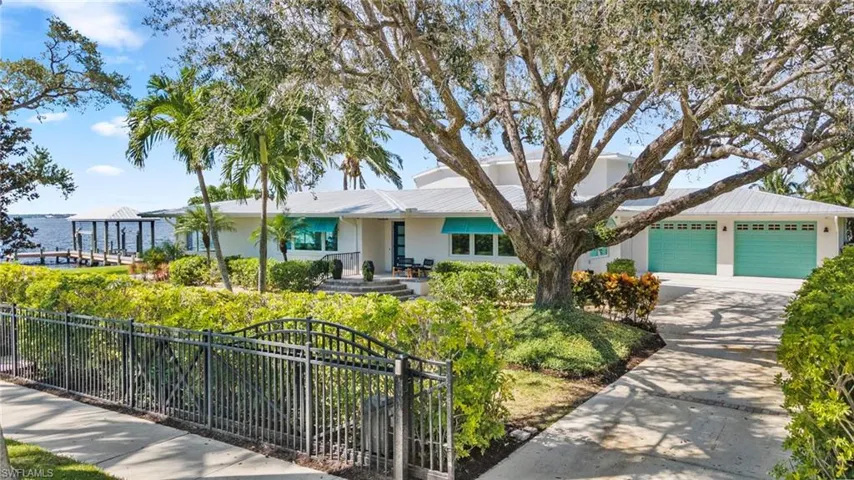View of front of property featuring a water view, concrete driveway, a metal roof, a fenced front yard, and an attached garage
