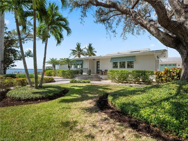 View of front of home with stucco siding, a front yard, and a water view