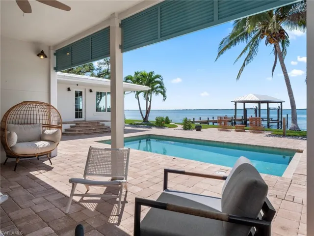 Outdoor pool with a water view, a gazebo, and a patio area