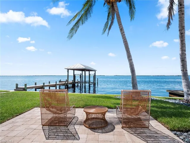 View of patio / terrace featuring a water view, an outdoor fire pit, a boat dock, and boat lift