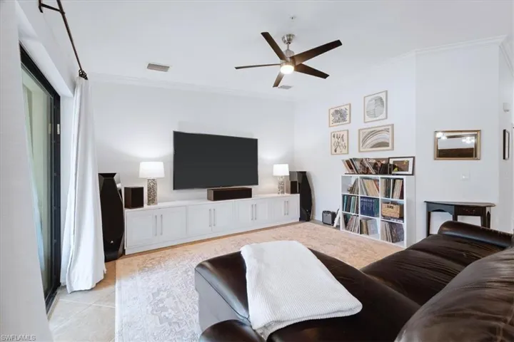 Living room with ornamental molding, ceiling fan, and light tile patterned floors