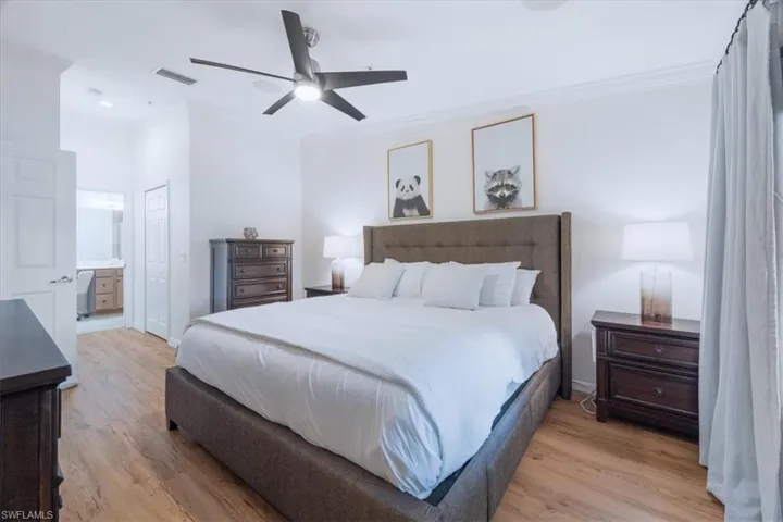 Bedroom featuring crown molding, light wood-style floors, ensuite bathroom, and a ceiling fan