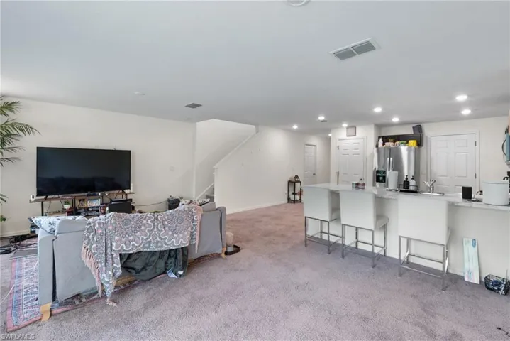 Living area featuring light carpet, stairs, and recessed lighting