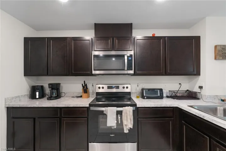 Kitchen with appliances with stainless steel finishes, light countertops, and dark brown cabinets