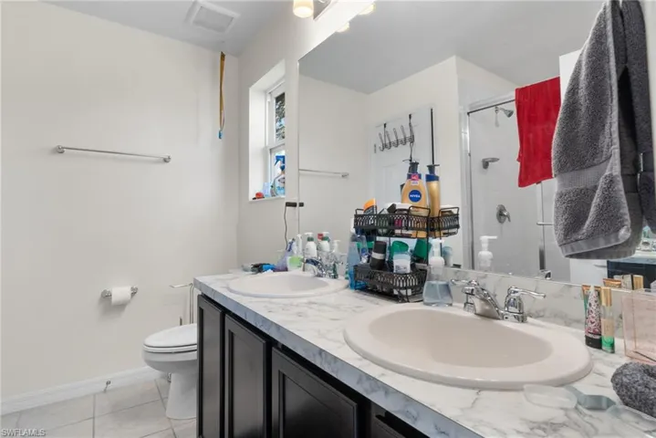 Full bath with a stall shower, double vanity, and tile patterned flooring