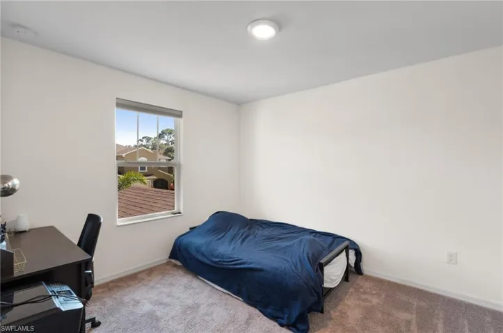 Carpeted bedroom featuring baseboards and a desk