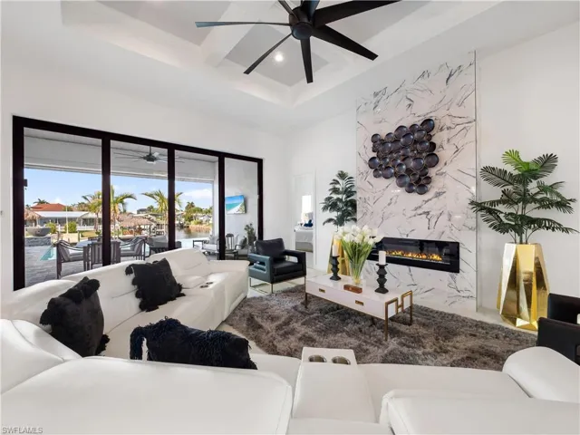 Living room with a ceiling fan, recessed lighting, a high end fireplace, and coffered ceiling