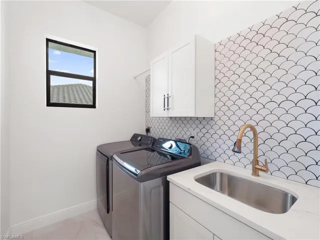 Laundry room featuring cabinet space, washing machine and clothes dryer, and light marble finish flooring