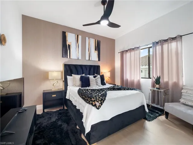 Bedroom featuring ceiling fan, wood finished floors, and an accent wall