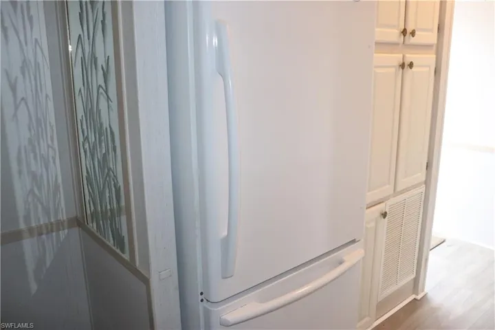 Room details with visible vents, wood finished floors, and freestanding refrigerator