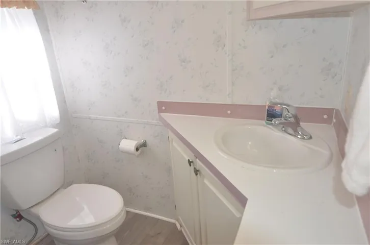 Bathroom with wallpapered walls, toilet, and vanity