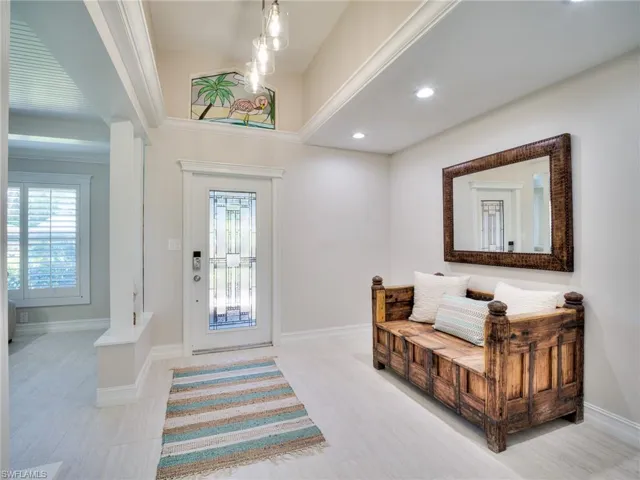 Bright entryway featuring a decorative glass-paneled door, recessed lighting, and a pendant light fixture