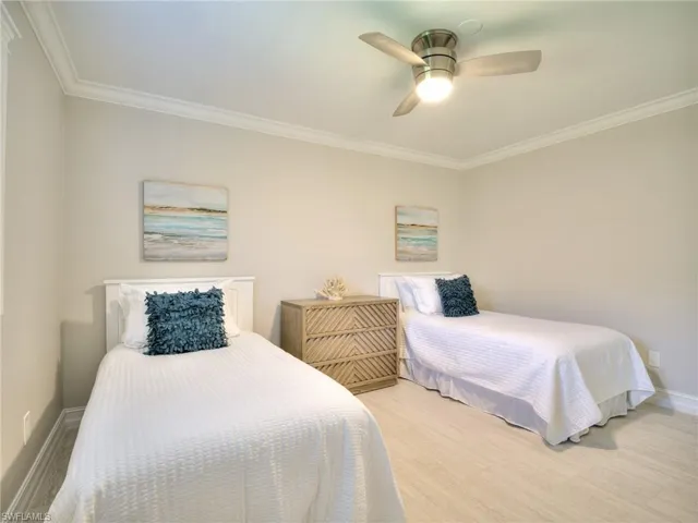 Room featuring light-toned walls, crown molding, and wood-finish flooring