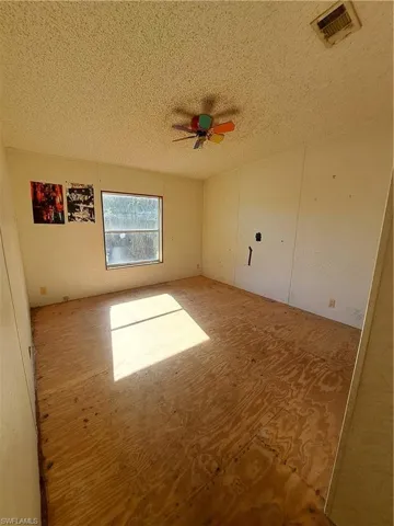 Empty room with a textured ceiling and ceiling fan
