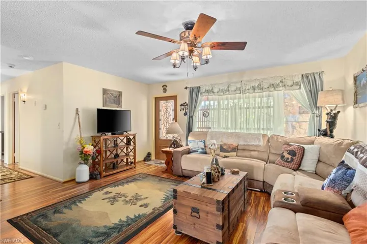 Living room featuring a textured ceiling, wood finished floors, and ceiling fan