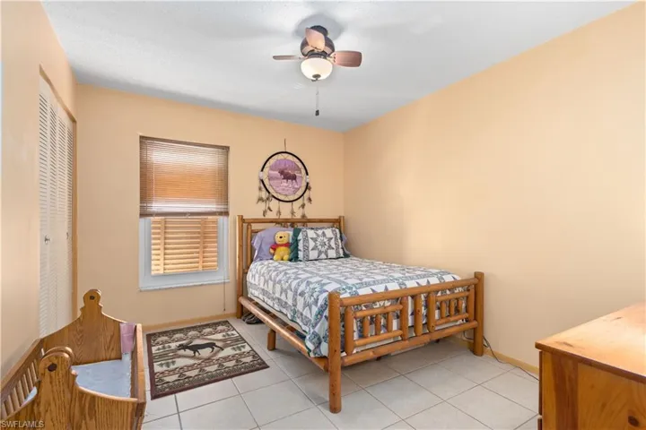Bedroom with light tile patterned floors, a ceiling fan, and a closet