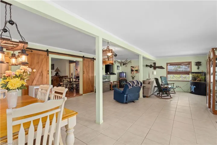 Living area with a barn door, light tile patterned floors, and wood walls