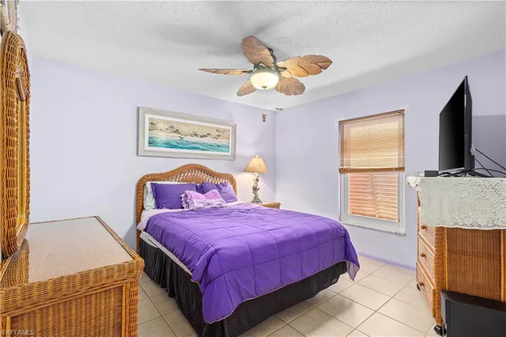 Bedroom with a textured ceiling, light tile patterned flooring, and a ceiling fan