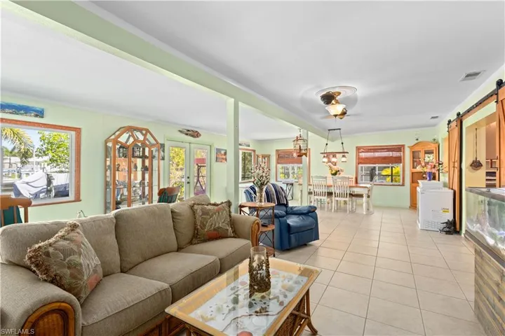 Living area featuring a barn door, light tile patterned floors, and french doors