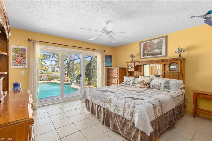 Bedroom featuring light tile patterned flooring, access to exterior, a textured ceiling, and a ceiling fan