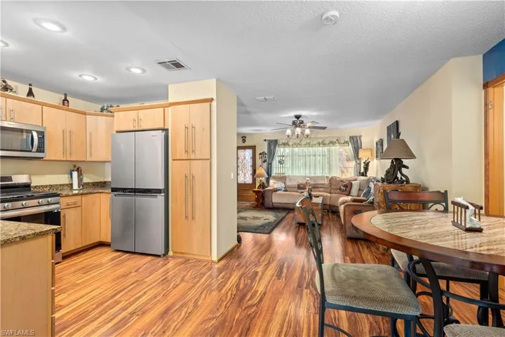 Kitchen featuring light brown cabinets, stainless steel appliances, light wood finished floors, dark stone countertops, and ceiling fan