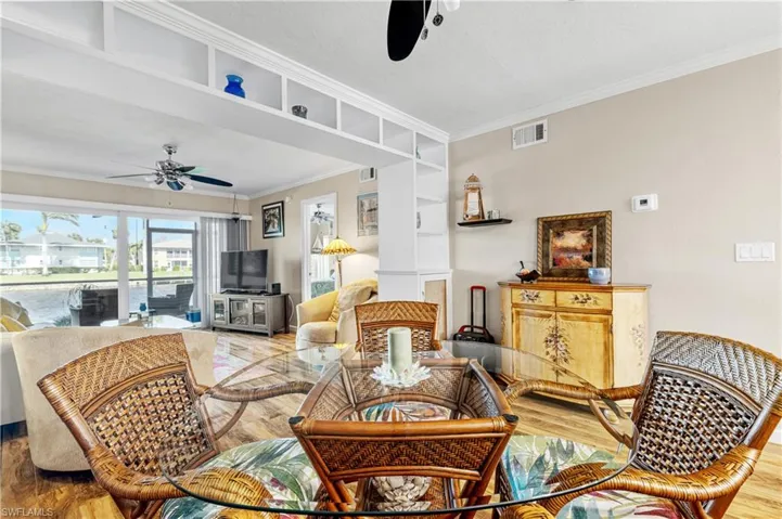 Dining area featuring ornamental molding, visible vents, ceiling fan, and wood finished floors