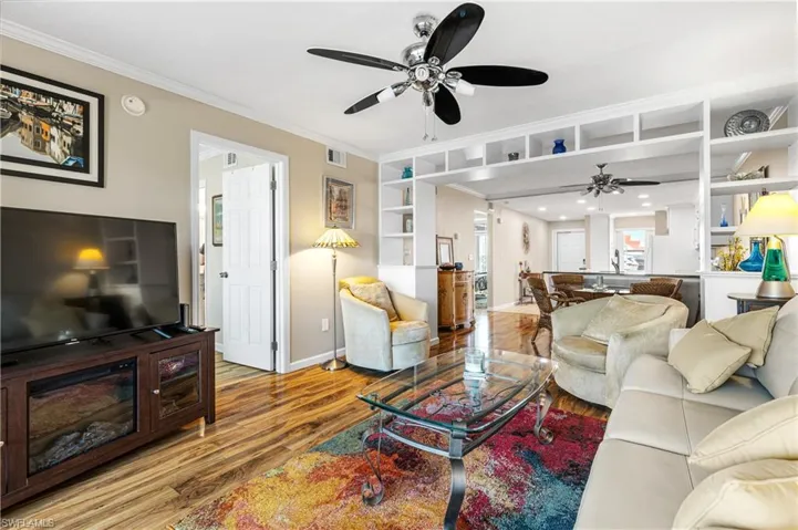Living area with baseboards, built in features, ornamental molding, ceiling fan, and wood finished floors
