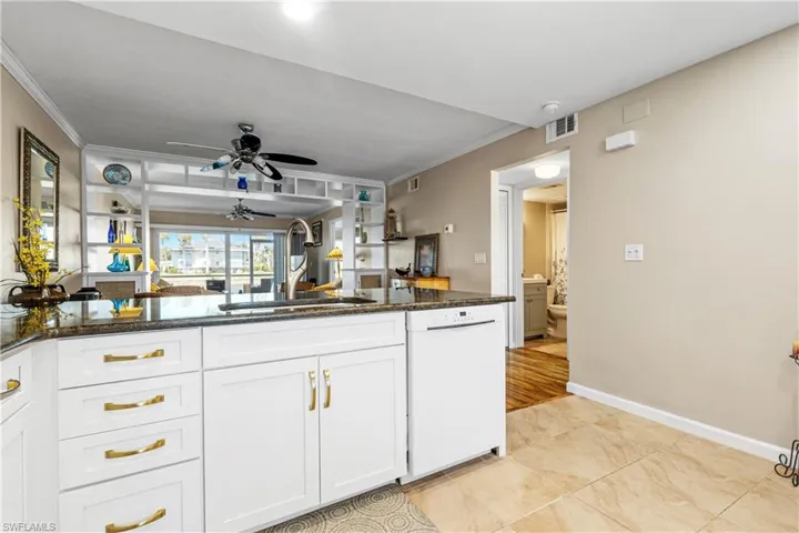 Kitchen with dishwasher, white cabinetry, ornamental molding