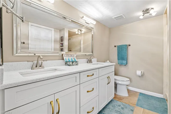 Full bathroom featuring tile patterned floors, a tile shower, and double sink