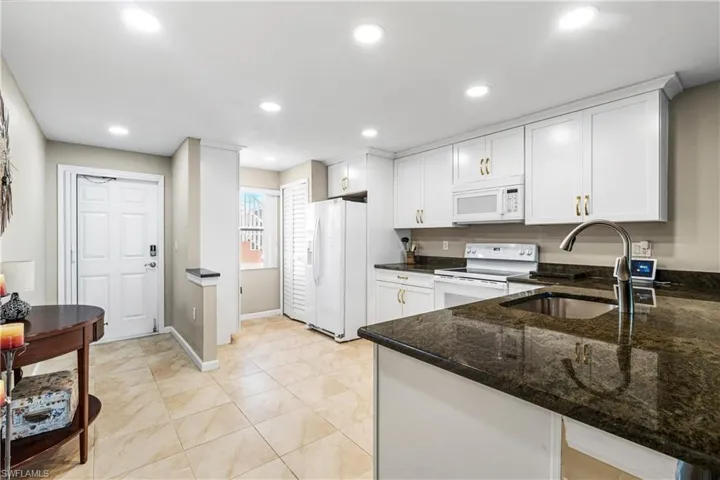Kitchen with granite countertops, recessed lighting, white appliances, white cabinetry, and a sink