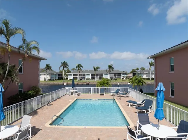 Pool with a patio, a residential view, fence, and a water view