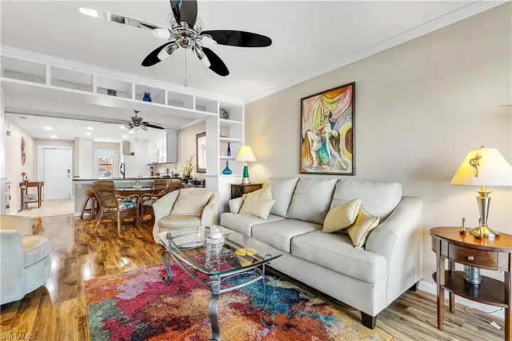 Living area with light wood finished floors, ornamental molding, and ceiling fan