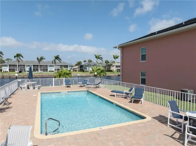 Pool with a patio area, fence, and a water view