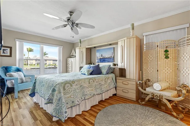 Bedroom featuring light wood-style flooring, ornamental molding, and ceiling fan