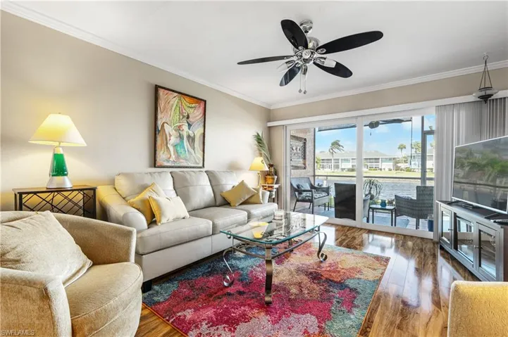 Living area with crown molding, wood finished floors, and ceiling fan