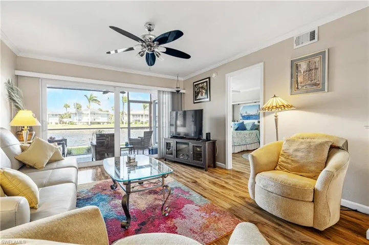 Living room with baseboards, a ceiling fan, crown molding, and wood finished floors