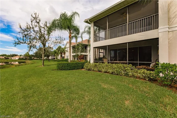 View of grassy yard featuring a sunroom and a balcony