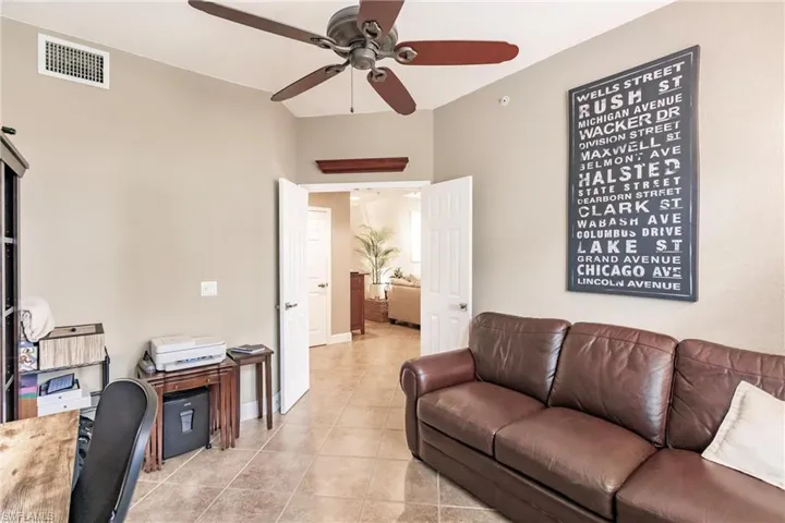 Living area with light tile patterned floors, a ceiling fan, and a desk