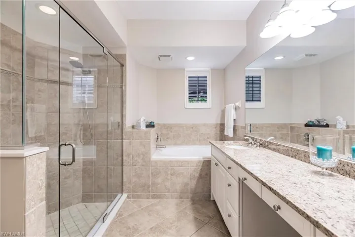 Full bath featuring vanity, a garden tub, a stall shower, and light tile patterned floors