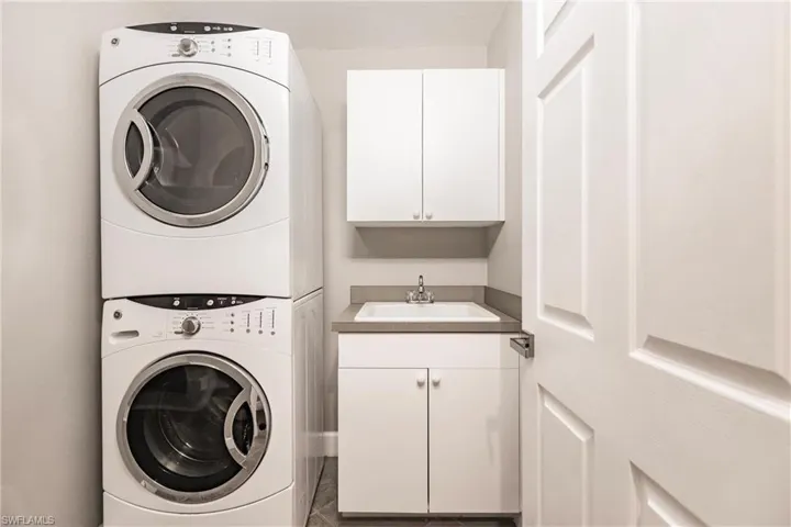 Washroom with stacked washer / drying machine and cabinet space