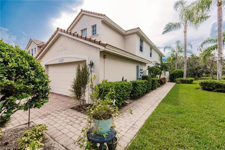 View of property exterior with a yard, stucco siding, a tiled roof, and a garage