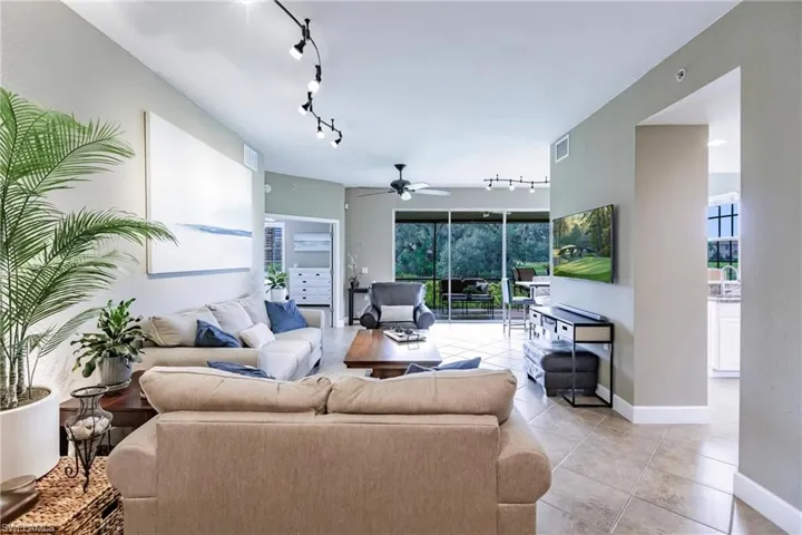 Living area featuring rail lighting, ceiling fan, light tile patterned flooring, and plenty of natural light