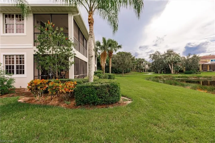 View of green lawn with a sunroom and a water view