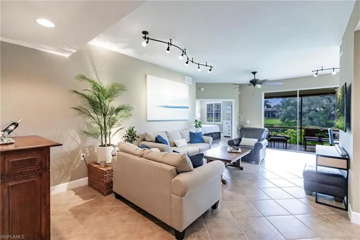 Living room featuring track lighting, light tile patterned flooring, and a ceiling fan
