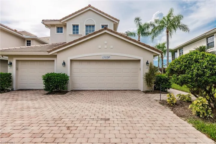 View of front of house with decorative driveway, a garage, stucco siding, and a tile roof