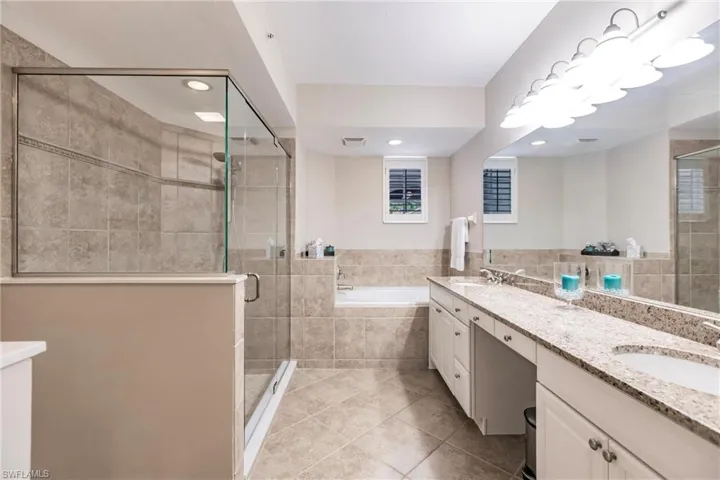 Full bath featuring double vanity, a stall shower, a garden tub, light tile patterned floors, and recessed lighting