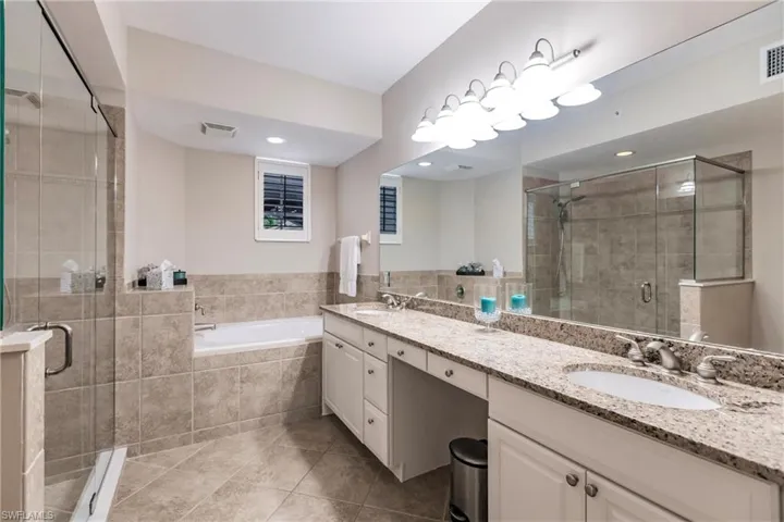 Bathroom with double vanity, a shower stall, a garden tub, and light tile patterned floors