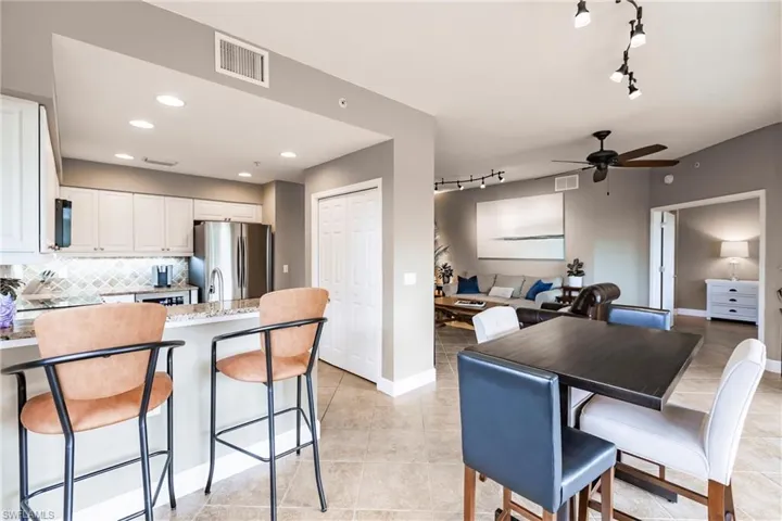 Kitchen with rail lighting, light stone counters, a peninsula, white cabinetry, and freestanding refrigerator